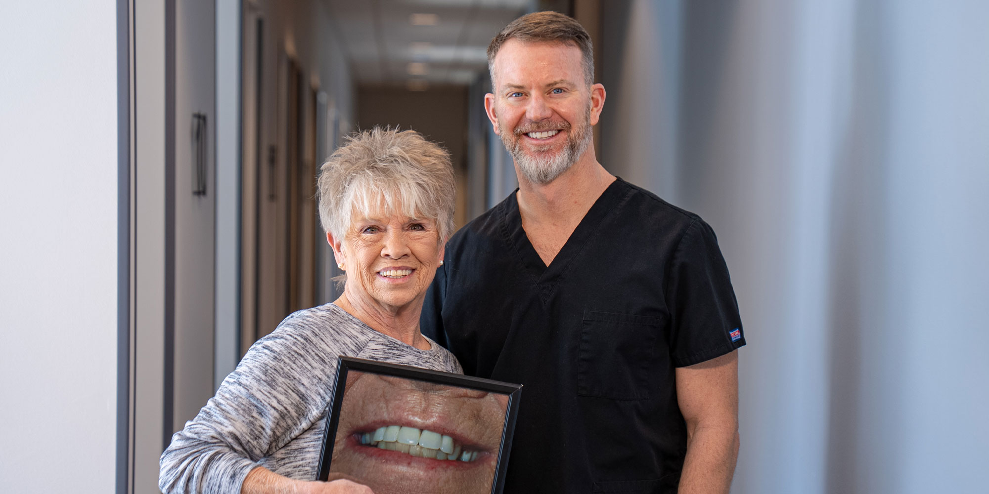 patient holding up a before and after photo of their old smile
